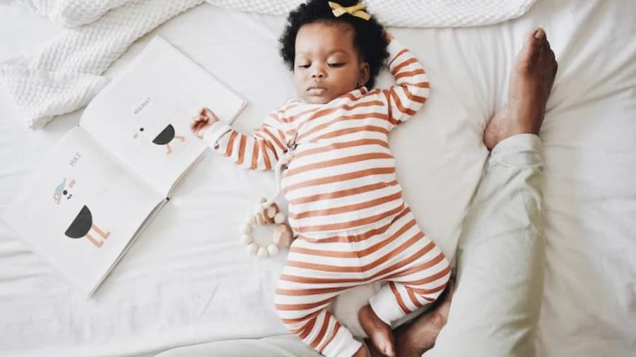 A baby peacefully sleeping on a bed, dressed in striped pajamas perfect for little ones