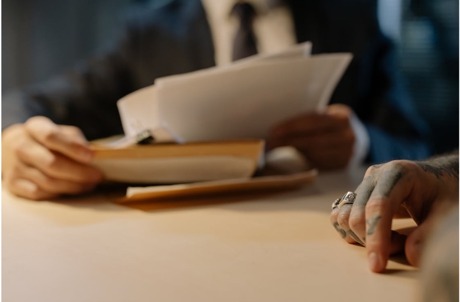 a lawyer going through documents sitting next to his client at a wooden table